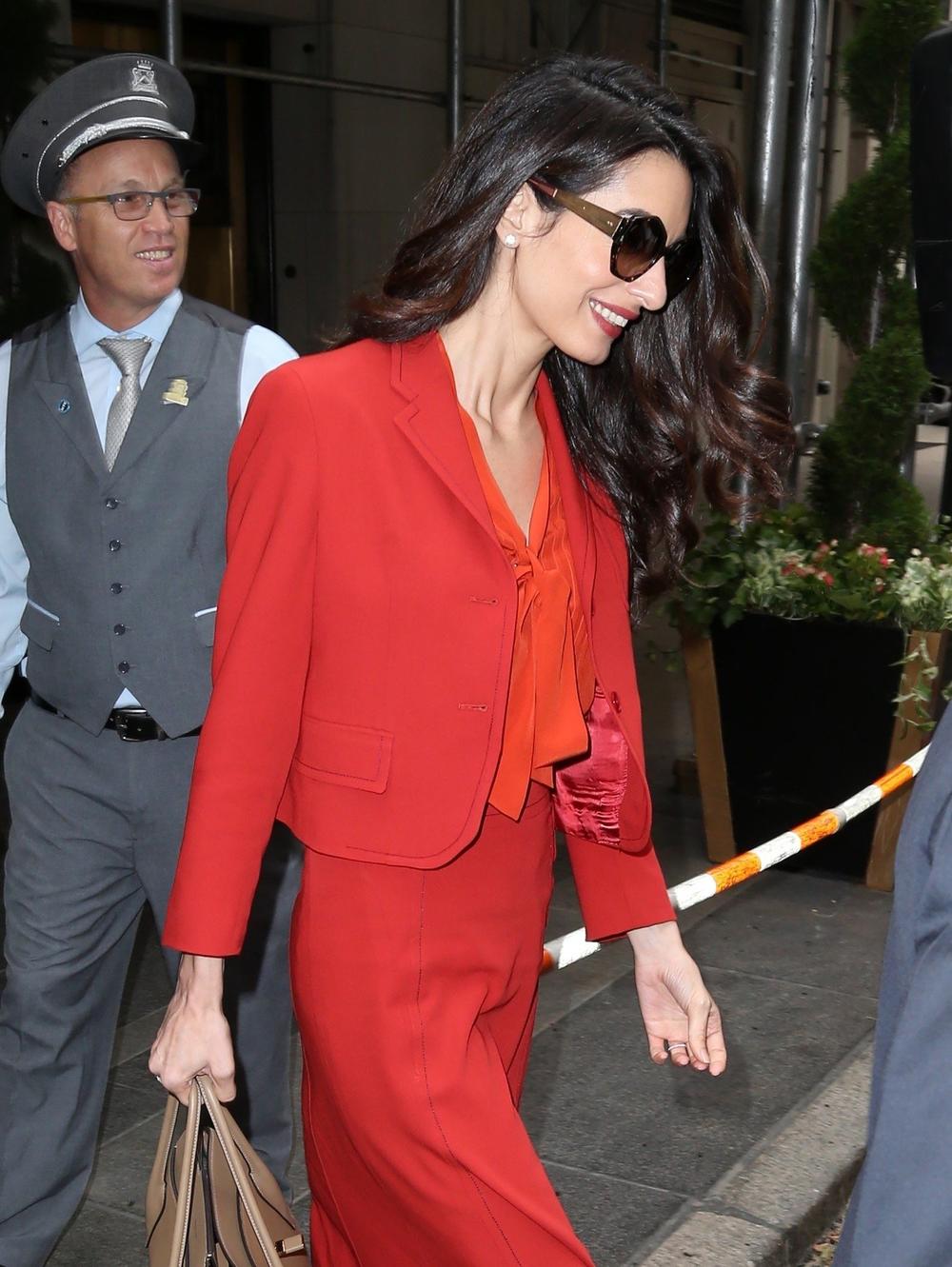 <p><strong>Amal Kluni </strong>blistala je od glave do pete u jarko crvenom kompletu, kojeg je uparila sa narandžastom košuljom i nude cipelama sa visokom štiklom.</p>