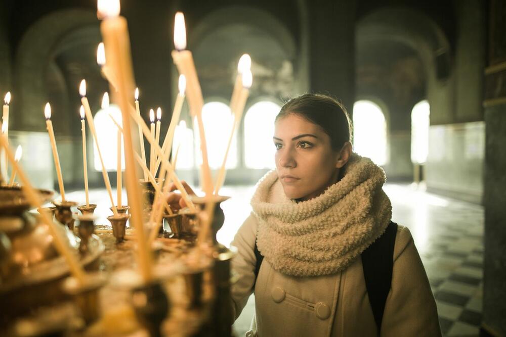 Devojka pali sveću u crkvi