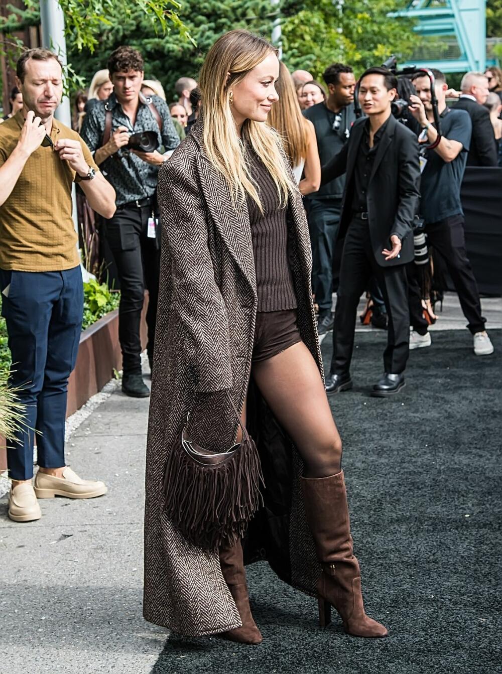Glumica i rediteljka Olivija Vajld u kombinaciji šortsa i kaputa na reviji modne kuće Michael Kors na Nedelji mode u Njujorku u septembru 2023. godine