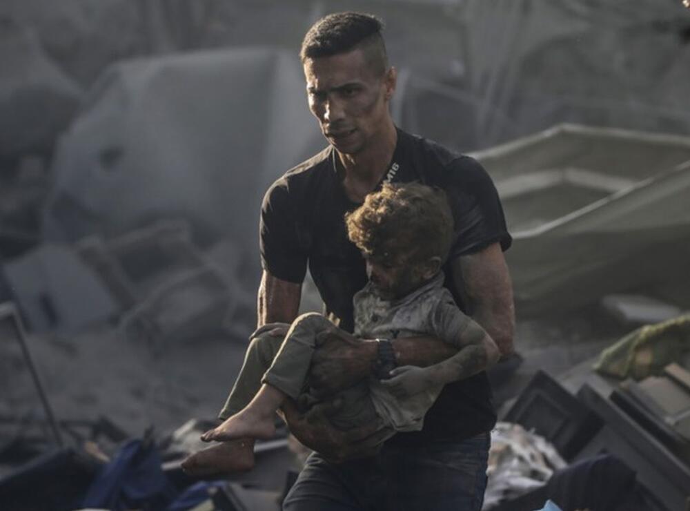 Čovek u Gazi nosi dete tokom potrage za preživelima nakon vazdušnog napada na Pojas Gaze 25. oktobra 2023.