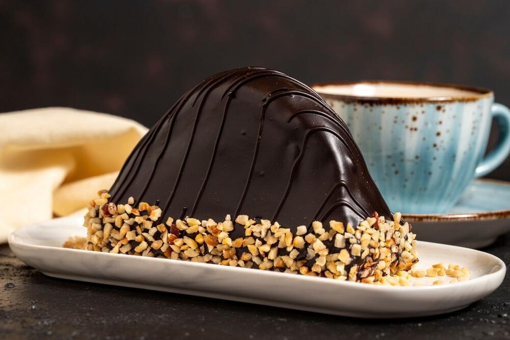 Malaga kolač možete posuti lešnicima i pre nego što sipajte čokoladni čanaš, a možete ga ukrasiti lešnicima nakon što sipate topljenu čokoladu