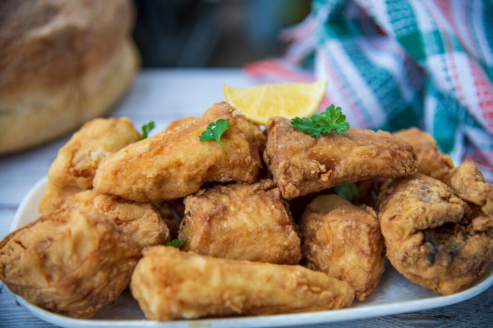 Serviran pohovani oslić za posnu slavu, s kriškom limuna