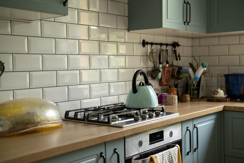 Mala kuhinja u zelenkastim tonovima s belim pločicama